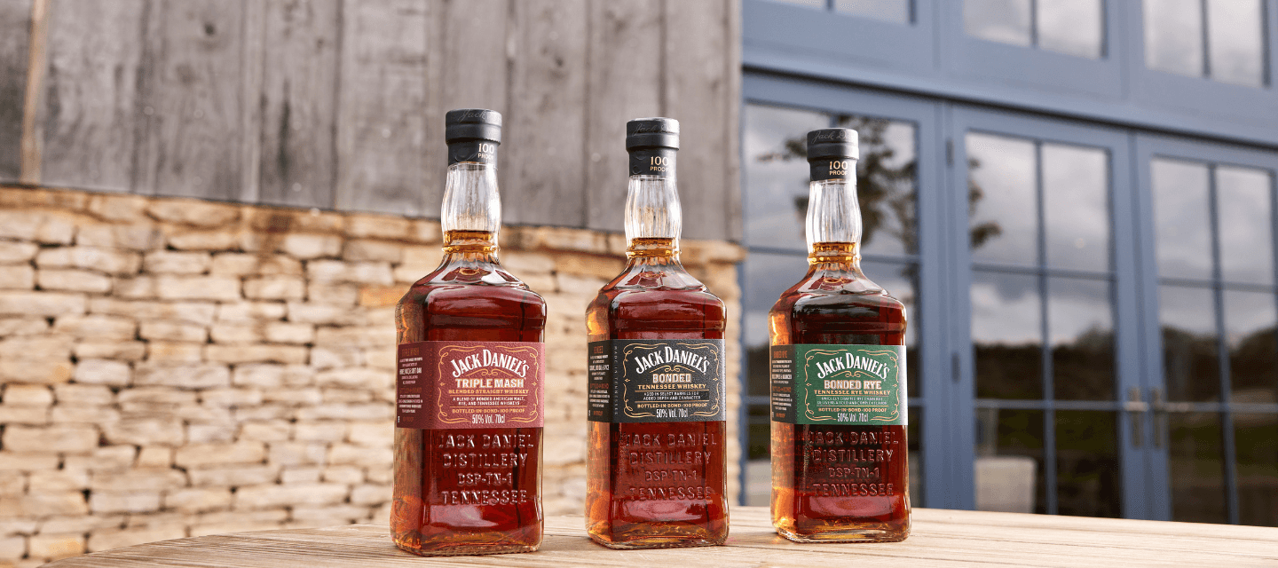 Picture of the three bottles of the jack daniel's bonded series in front of the jack daniel's distillery