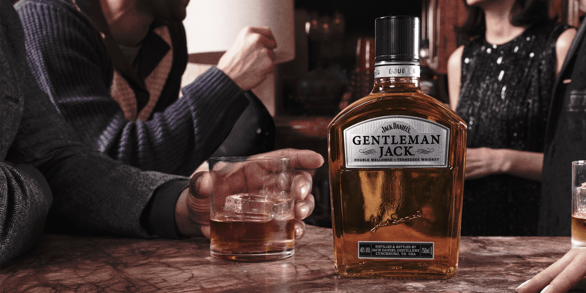 A bar top with a bottle of Gentleman Jack and a glass of whiskey